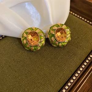 Vintage gold-plated round earrings with green enamel leaves and orange faceted gemstone