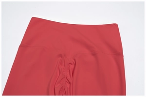Dettaglio dei leggings yoga rossi a vita alta con fascia bianca e cucitura scrunch butt
