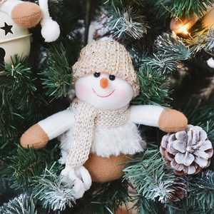 Knitted snowman Christmas ornament with sequin details hanging on a festive tree