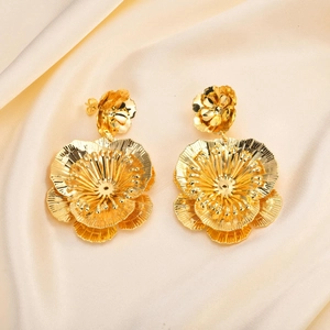 Large golden flower earrings with double-layered petals on elegant silk background