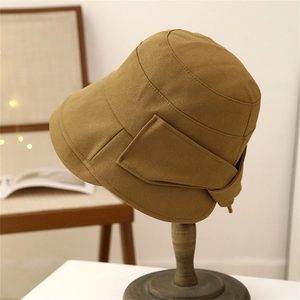 Classic khaki wide brim sun hat with ribbon bow detail on a stylish wooden stand