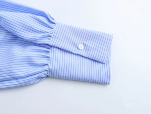 Close-up of blue and white striped shirt cuff with a single white button detail