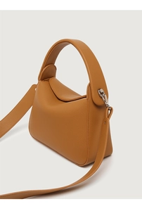 Macro detail of brown litchi grain leather bag with silver buckle and handle