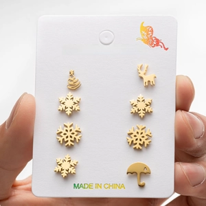 Close-up of gold stainless steel stud earrings featuring snowflake and reindeer designs