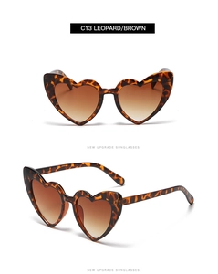 Detail view of heart-shaped sunglasses featuring leopard print frame and brown gradient lenses
