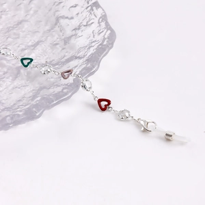 Detail of silver eyewear chain with colorful enamel hearts and faceted clear beads
