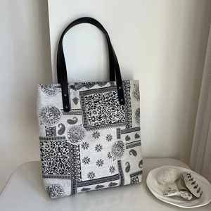 Detail of paisley print cotton linen tote bag with black handles and metal rivets