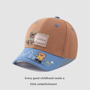 Detail of baby baseball cap featuring cartoon bear patch and printed skateboard patterns