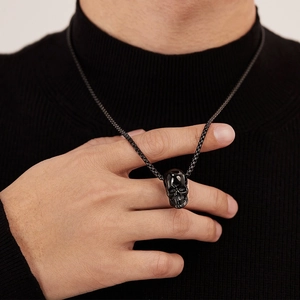 Close-up of polished black stainless steel skull pendant with box chain on a model