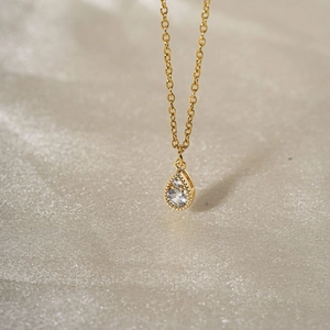Collier goutte d'or élégant avec pendentif en zircone sur un tissu en soie lisse