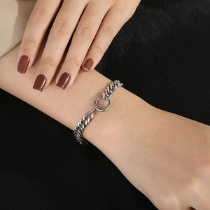 Detail of silver titanium steel curb chain bracelet with circular spring clasp on wrist