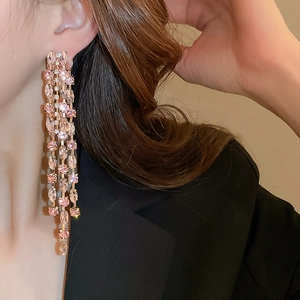 Close-up of pink zircon long tassel earrings worn by a model in a black suit