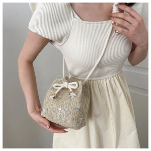 Détail de ce sac seau en paille avec broderies florales et fermeture en corde tressée
