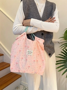 Pink cartoon rabbit embossed canvas tote bag with floral texture held by a person