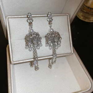 Detailed view of silver tassel drop earrings with pearls and zircon in a jewelry box
