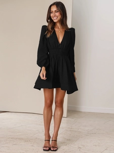 Dettaglio dell'abito nero a maniche lunghe con scollo a V e vita plissettata chic