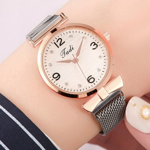 Close-up of rose gold watch dial with rhinestone markers and stylish bow-shaped lugs
