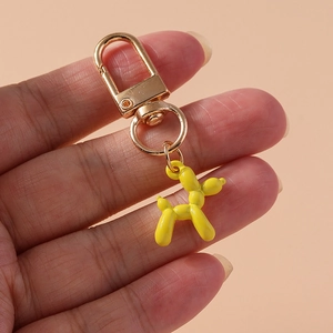 Detail of yellow balloon dog keychain with golden metal hook held in hand