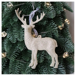 Sparkling white glitter reindeer ornament hanging on a Christmas tree with festive lights