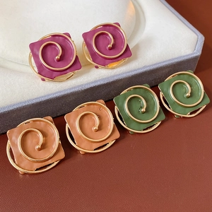 Detail view of square vintage earrings with golden spiral texture in purple, brown and green