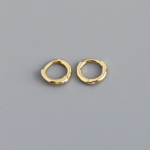 Macro shot of polished gold huggie hoop earrings with seamless invisible clasp design