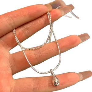 Minimalist double layer stainless steel necklace with water drop pendant shown in hand