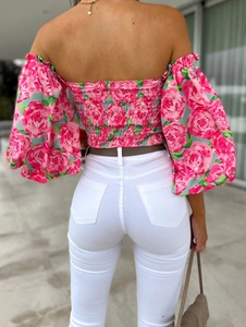 Back view of pink floral off-shoulder top with puff sleeves and white slim-fit trousers