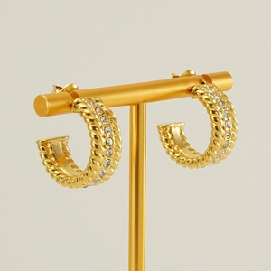 Detailed view of gold-plated twisted C-hoop earrings with sparkling zircon inlay