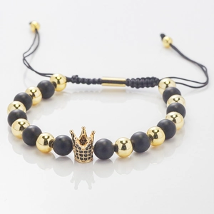 Detail of adjustable braided bracelet with black beads and gold crown charm with zircons