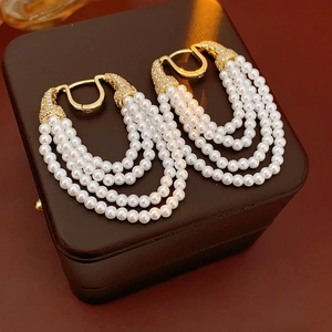 Detailed view of vintage gold multi-layer pearl earrings with sparkling rhinestones set