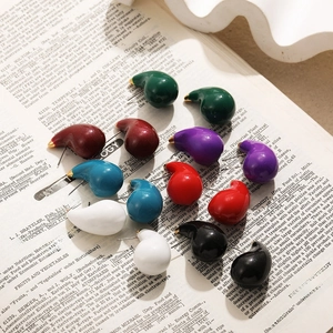 Colorful enamel water drop stud earrings in vintage minimalist aesthetic on antique books