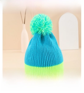 Detail of teal chunky knit beanie with neon green ribbed cuff and fluffy top pompom