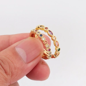 Detalle de dos anillos dorados con cristales multicolores de talla marquesa y redonda