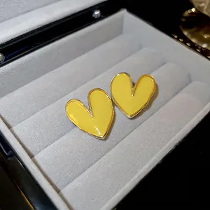 Boucles d'oreilles cœur jaune minimalistes avec bord doré dans une boîte à bijoux