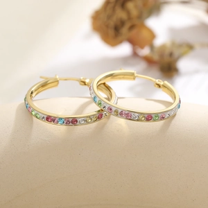 Close-up of golden hoop earrings featuring vibrant multicolored rhinestones on the band
