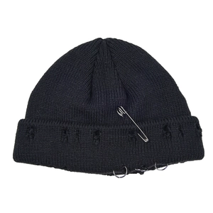 Detailed view of black distressed knit beanie hat with safety pin and metal rings