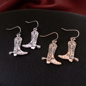 Macro shot of vintage style cowboy boot drop earrings in gold and silver finishes