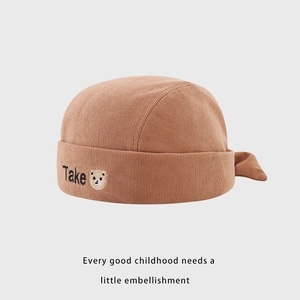 Détail du bonnet bébé en velours côtelé marron avec broderie d'ours et texte Take
