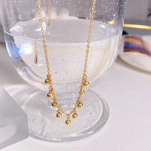 Elegant gold plated stainless steel beaded tassel necklace on a glass with water