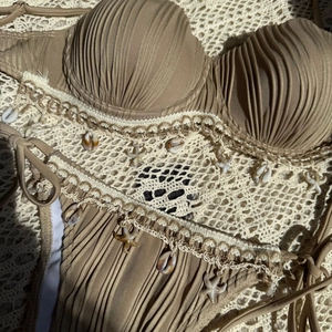 Detailed macro shot of tan bikini with handmade crochet lace, sea shells, and starfish charms