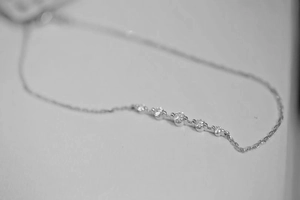Primer plano de cinco circonitas redondas en una fina cadena de plata de ley 925