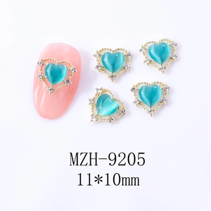 Détail macro du bijou d'ongle cœur œil de chat avec dentelle dorée en 11x10mm