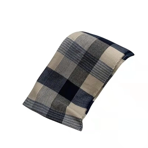 Detail view of blue plaid wool blend scarf with tassel fringe on a white background
