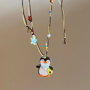 Detail view of penguin avocado pendant necklace with colorful beads and starfish