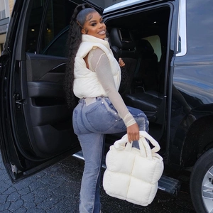 Detailed street style view of a cropped white puffer vest paired with a denim handbag