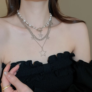 Detail of layered silver necklace with star pendants and pearl beads on a model