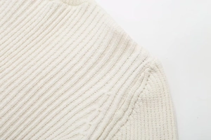 Macro shot of white ribbed knit fabric detailing the soft texture and seam of the dress