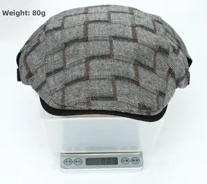 Detail shot showing the vintage plaid flat cap weighing approximately 80g on a digital scale