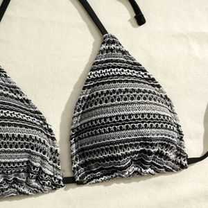 Close-up of black and white crochet triangle bikini top showing detailed knit texture