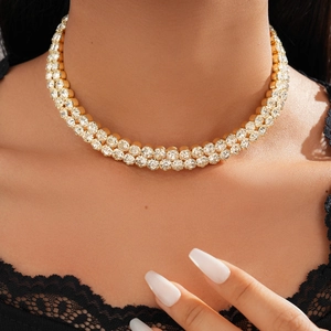 Close-up of elegant double-layered gold necklace with sparkling crystals on model